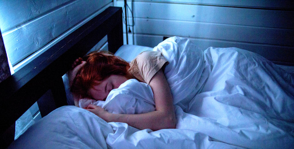 A woman resting peacefully in a cozy bed during these homebound times.