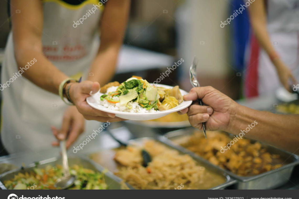 A man handing a plate of food to another person during an amazing breakfast.