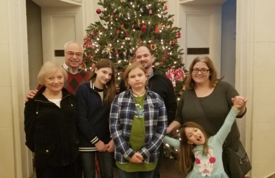 A family on the 19th floor posing in front of a christmas tree.