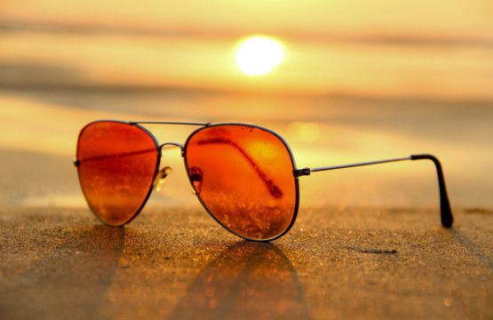 A pair of sunglasses on the sand at sunset, symbolizing summer.