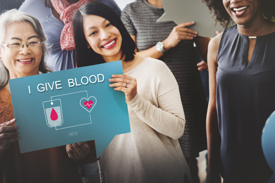 A community holding up a sign that says i give blood.