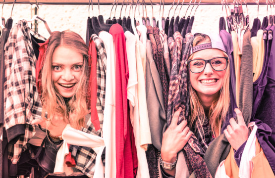 Two women browsing a rack of clothes at a flea market.