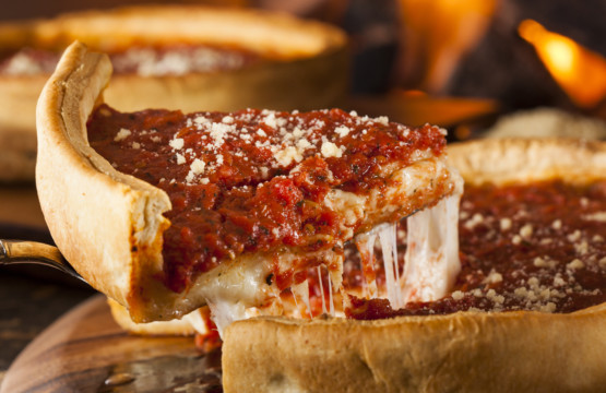 A slice of deep dish pizza is being taken out of a pan at a pizza day party.