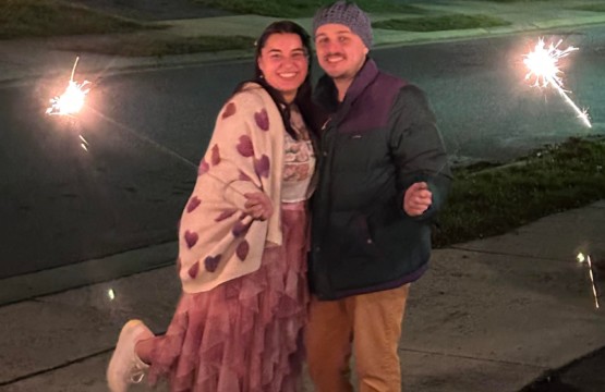 Two individuals holding sparklers on a sidewalk, featured in the Resident Spotlight: Isabella F. and Gabriel E. on the 13th floor.