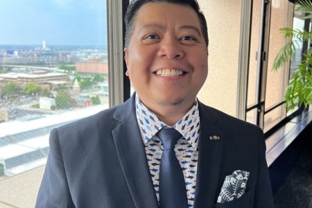 A man in a suit standing in front of a window on the 16th Floor.