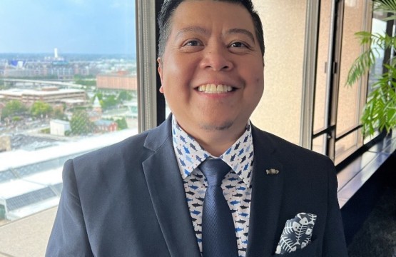 A man in a suit standing in front of a window on the 16th Floor.