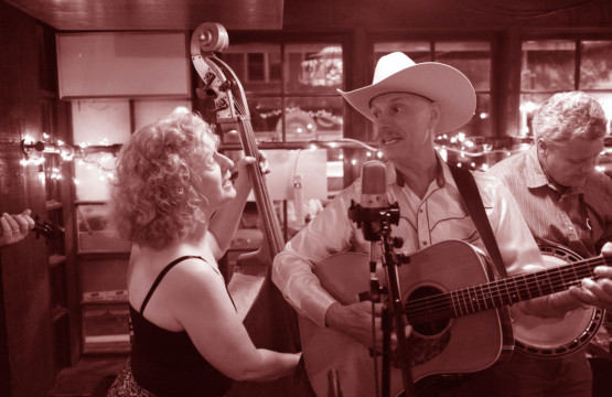 A man in a cowboy hat playing an acoustic guitar at Music In The Courtyard - Blue Spruce Bluegrass.