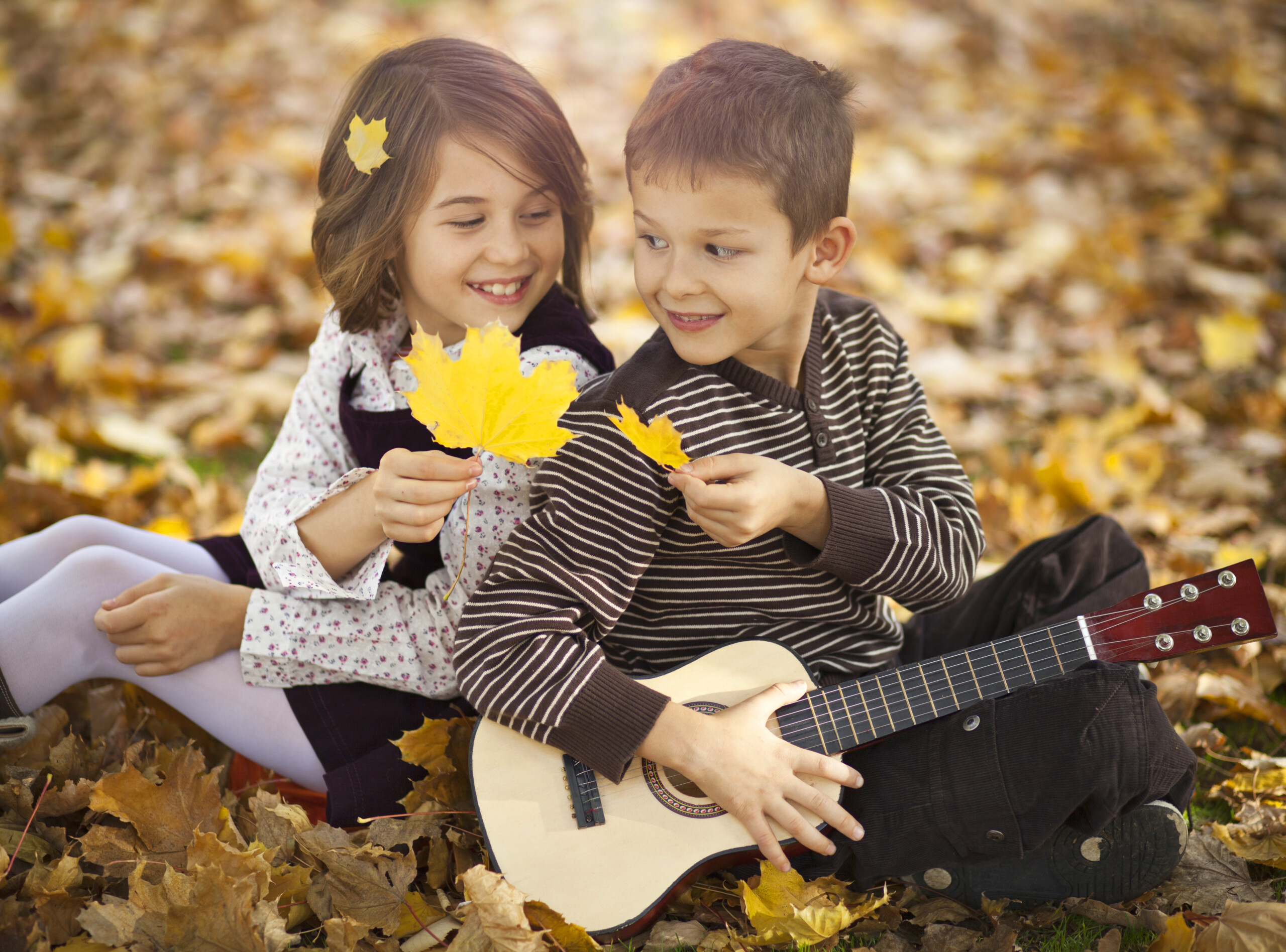 Children playing acoustic guitar autumn leaves.